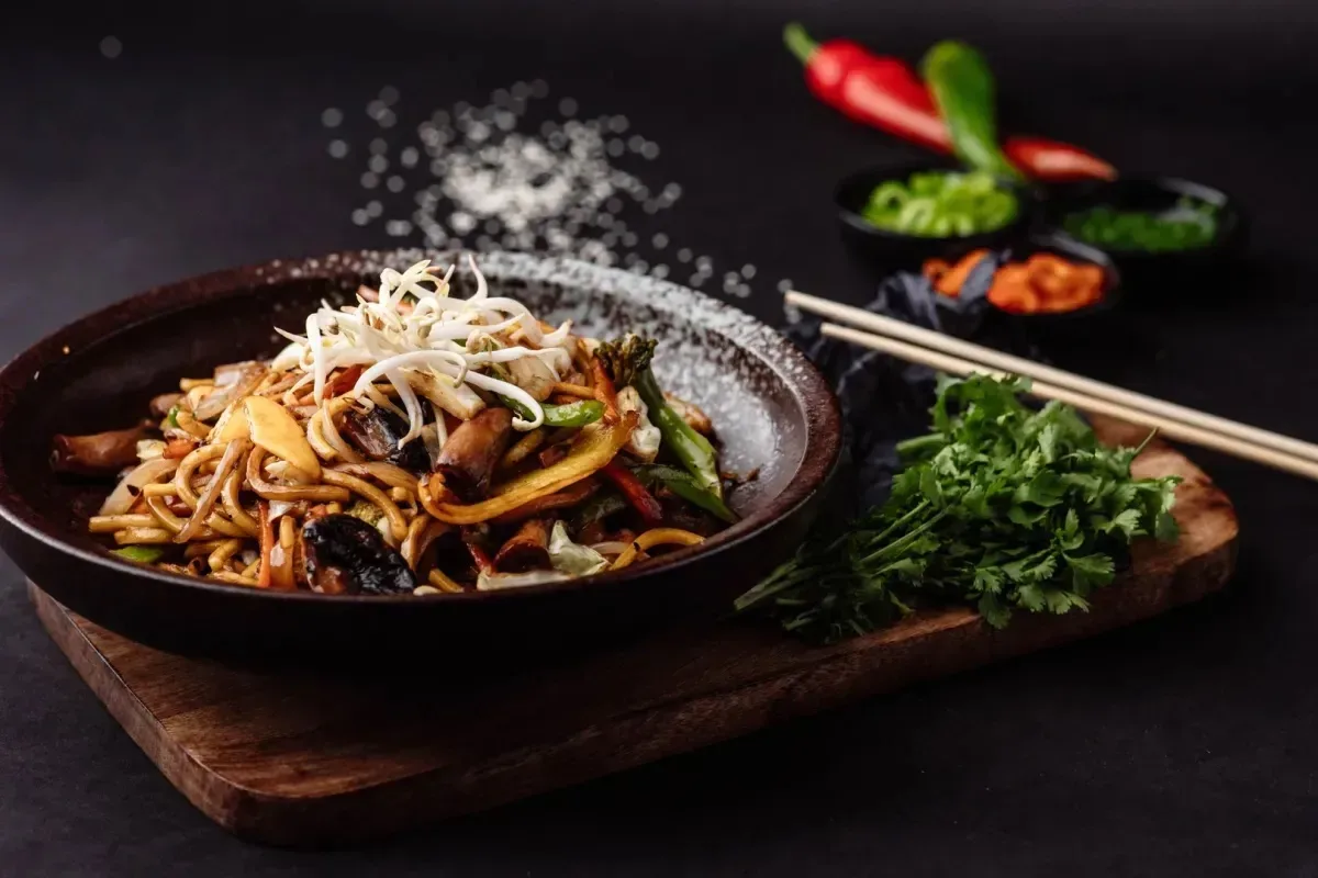 נודלס בוואק, Take Me Wok, מוגשים על צלחת כהה עם תבלינים טריים